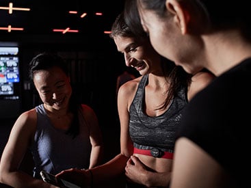 Three women in a gym looking at the Myzone app