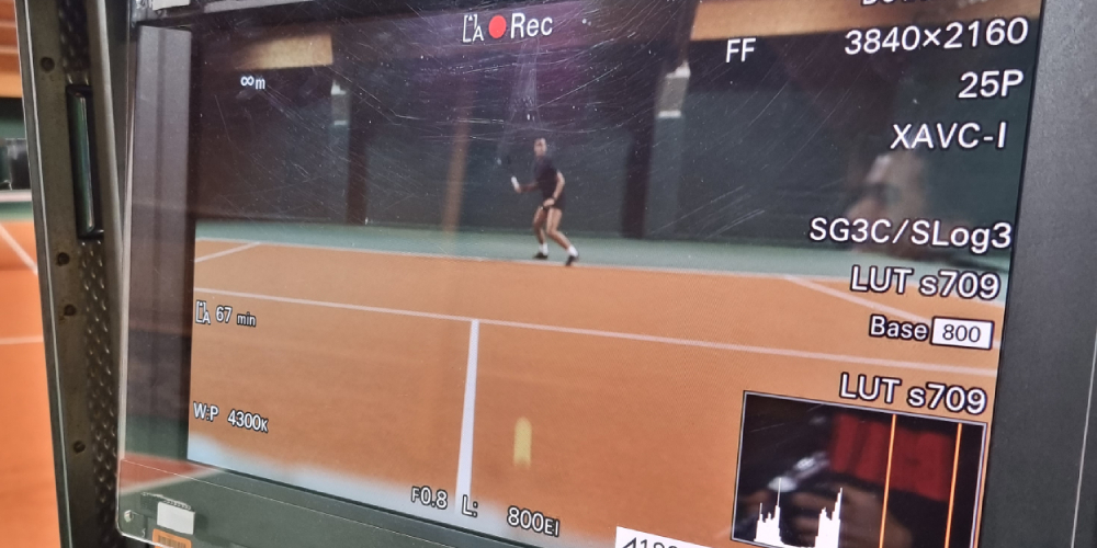 A video monitor showing a woman playing tennis on a David Lloyd court