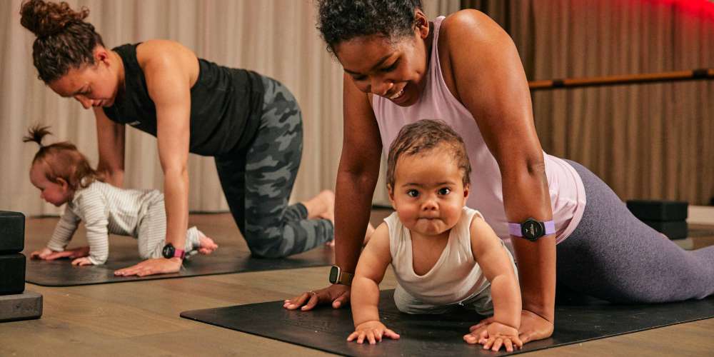 A baby looking at the camera while mum takes part in a baby yoga class