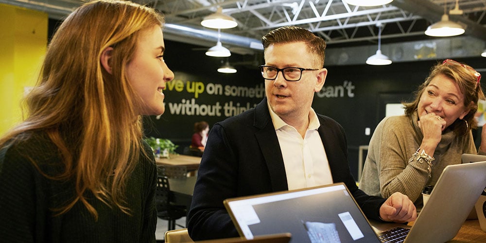 Three professionals in a discussion at a desk