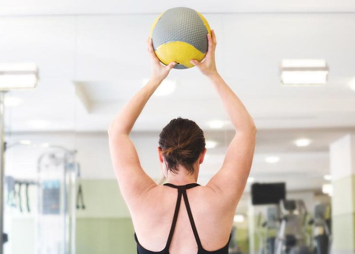 woman lifting medicine ball