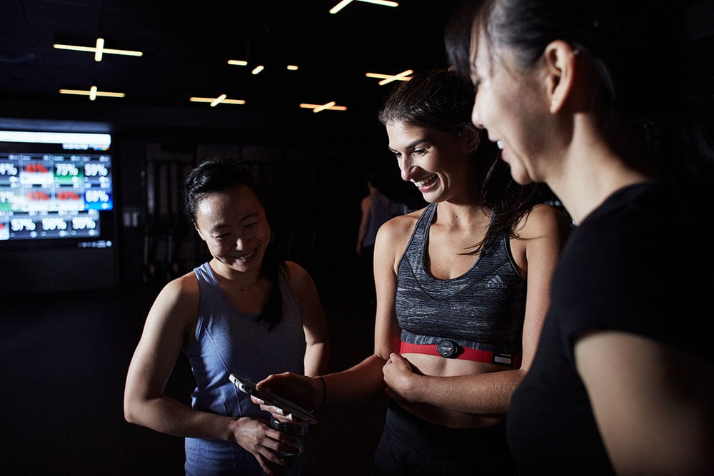 Three women looking at a smartphone in the gym
