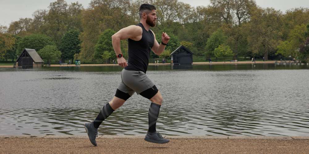 Man running by the side of a lake, wearing a heart rate monitor