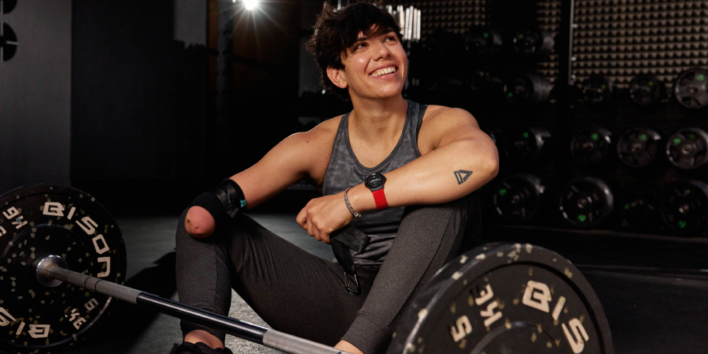 Paralympian Joana Calado sitting down next to a barbell, wearing a heart rate monitor