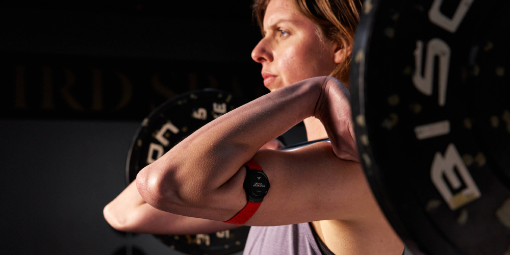 British Champion swimmer Rebecca Guy lifting a barbell in front rack, wearing a heart rate monitor