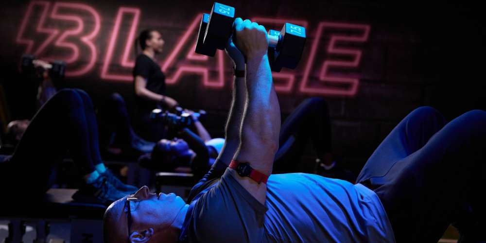 Gym members lifting dumbbells in a group exercise Blaze studio