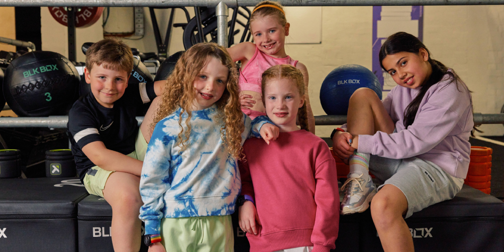 Children sat on fitness equipment in a gym