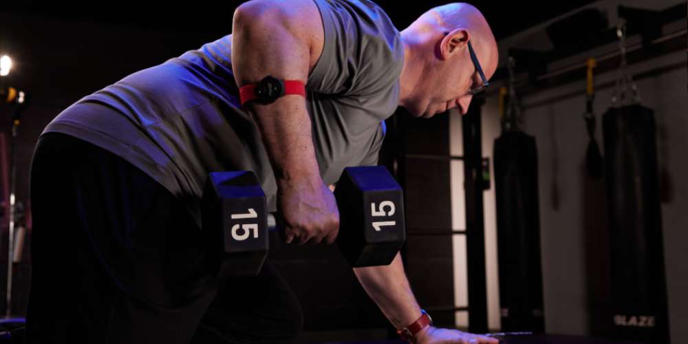 Man lifting a dumbbell, wearing a heart rate monitor
