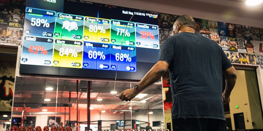 Man in UFC GYM skipping in front of a Myzone screen