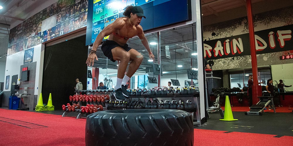 Man jumping over a tyre in UFC GYM