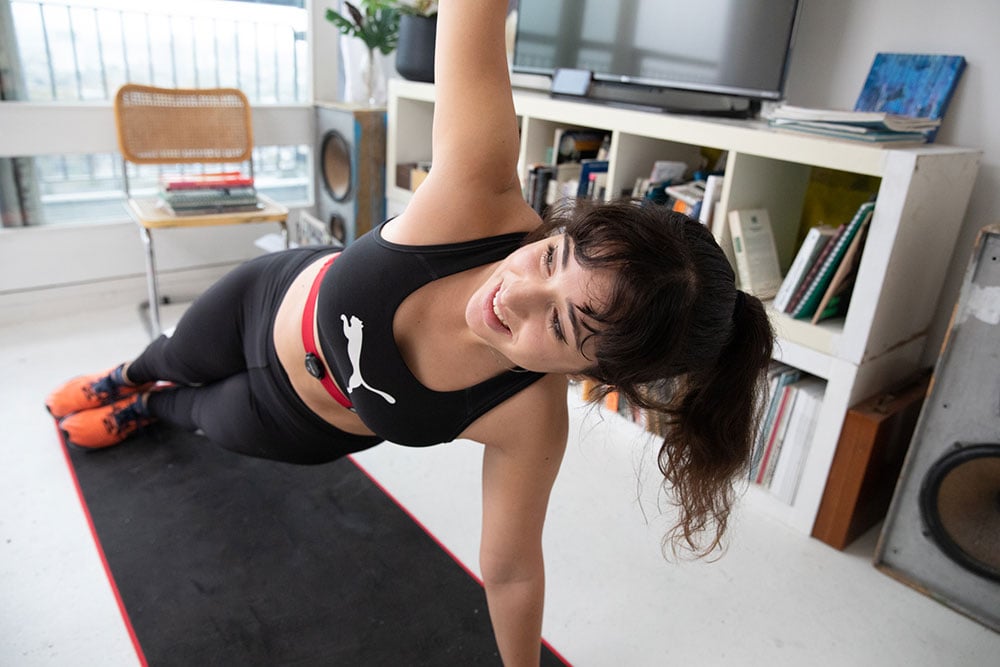 Woman doing bodyweight exercises at home wearing a Myzone heart rate monitor