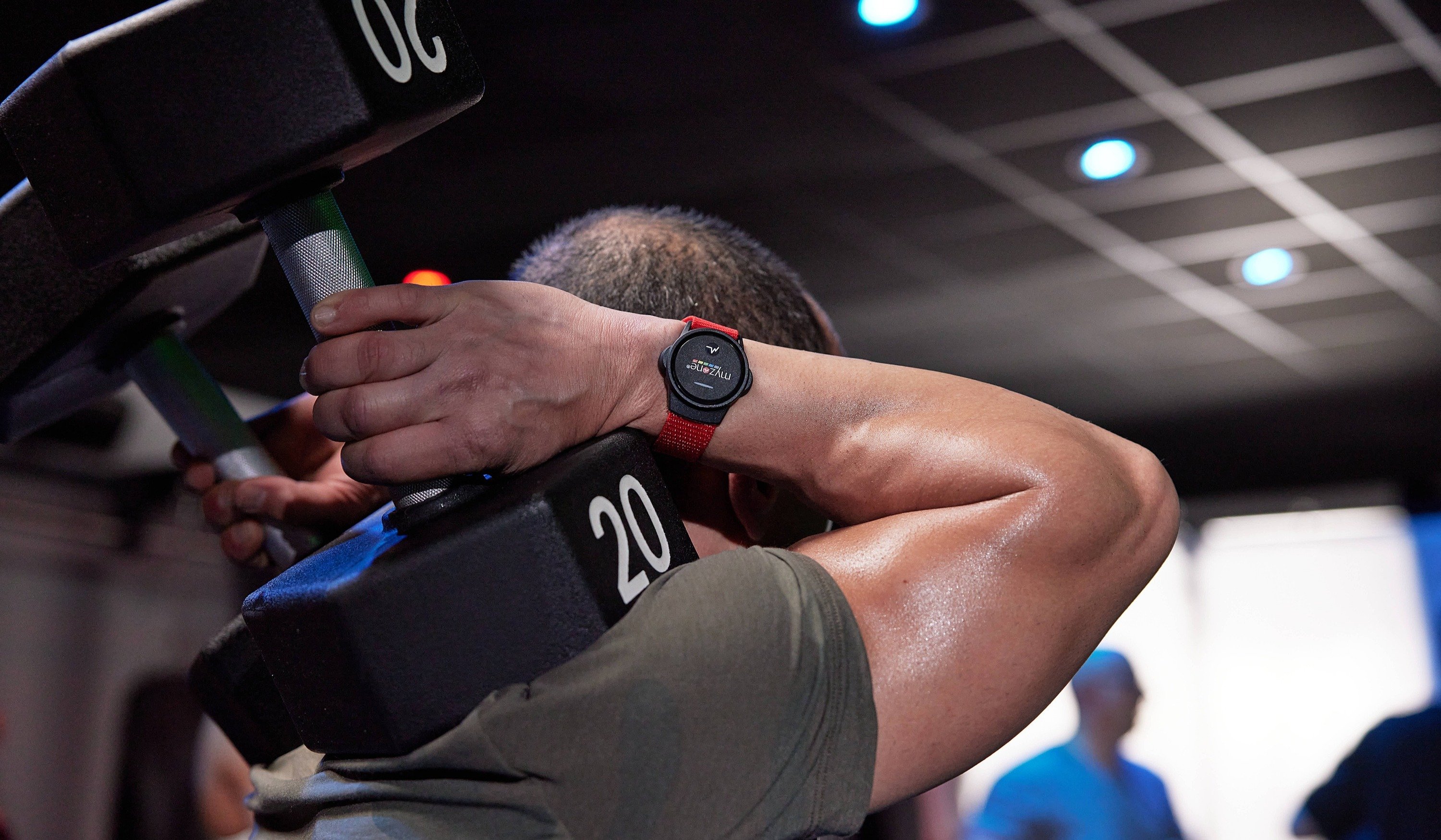 Myzone user lifting weights above their head while wearing the MZ-Switch