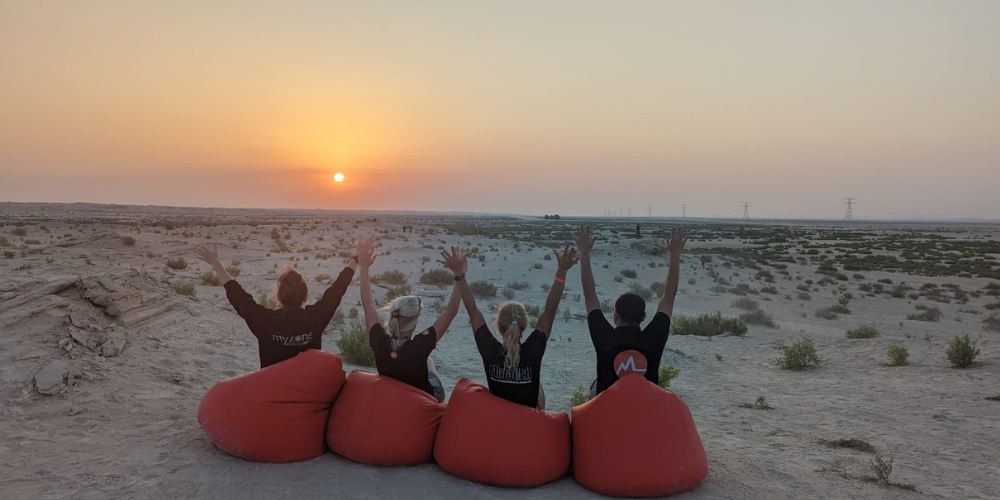 Four people celebrating on bean bags while watching the sunset