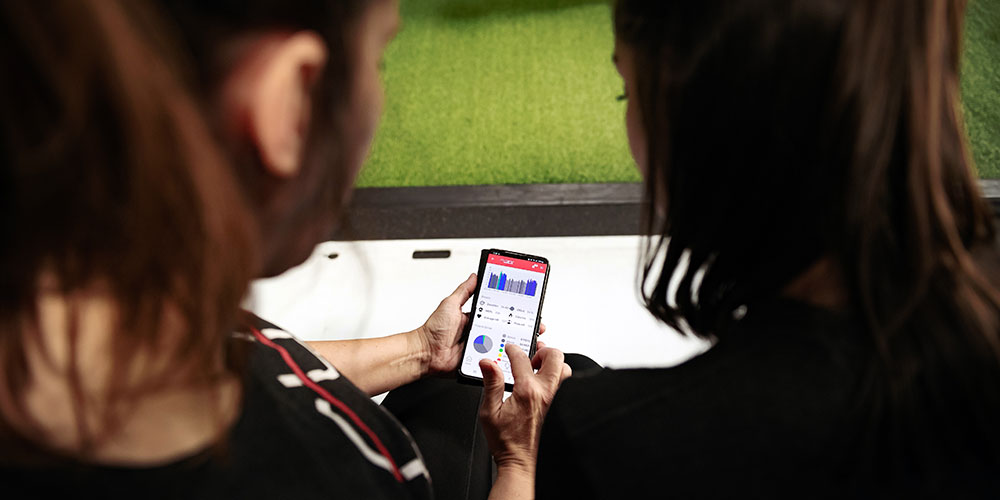 Two women looking at the Myzone app on a smartphone