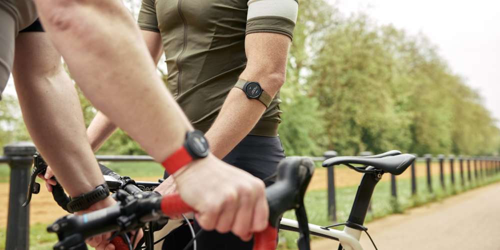 Two cyclists wearing MZ-Switch heart rate monitors, one with it on thier wrist; the other on their arm