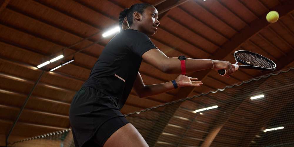 Woman playing tennis wearing a heart rate monitor on her arm