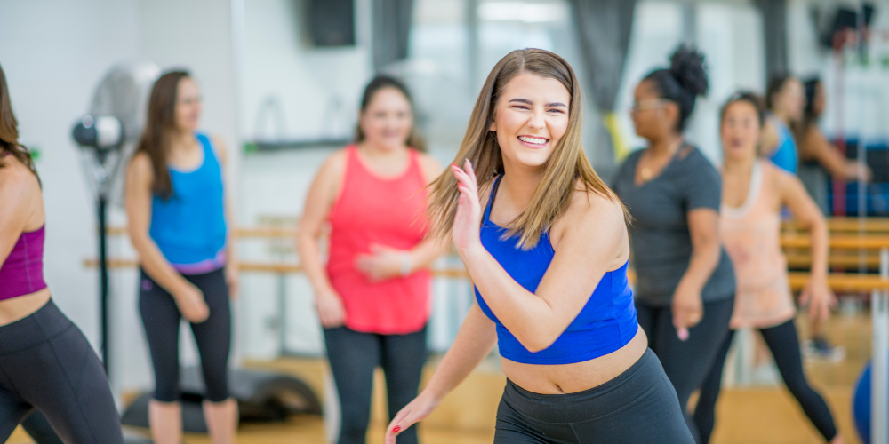 Woman smiling at the front of an exercise class